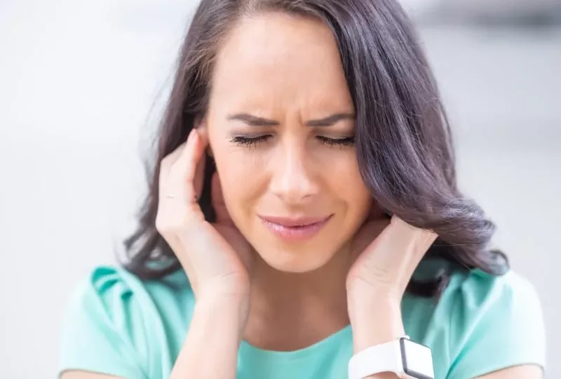Young woman have headache migraine stress or tinnitus - noise whistling in her ears.